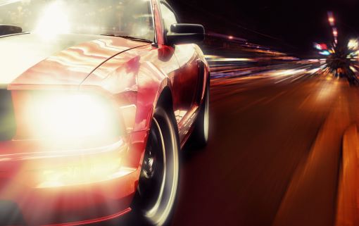 Sports car driving at night through blurred lights